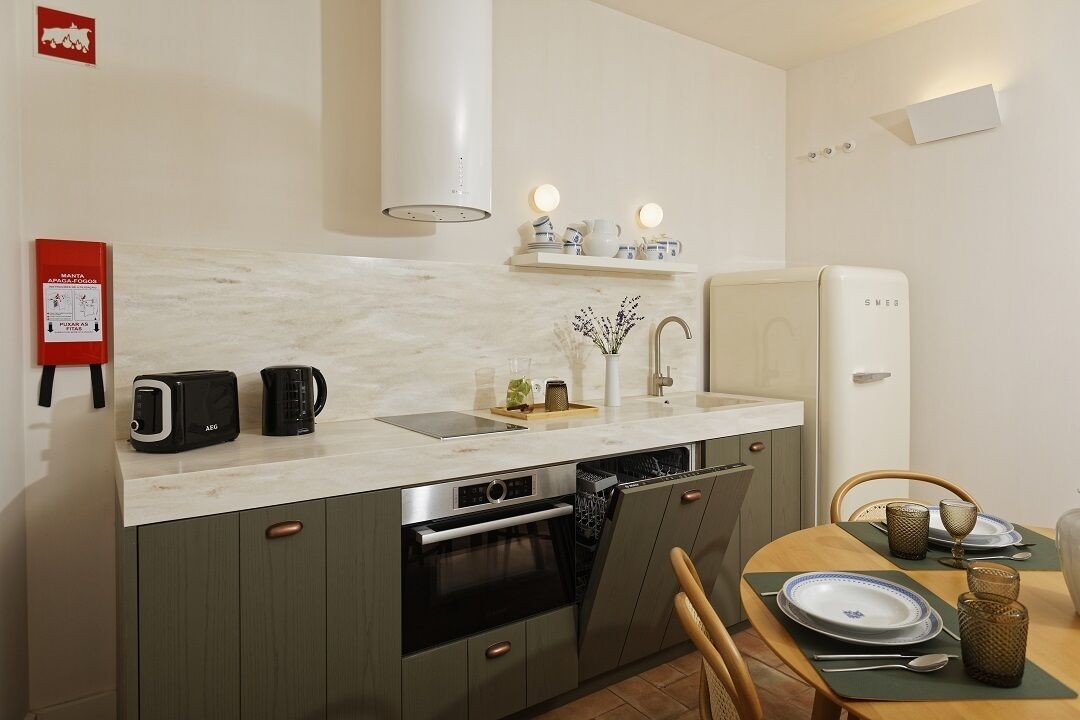 A compact kitchen with a built-in oven, a microwave, and a coffee maker. There is a dining table with chairs and a small shelf above the sink.