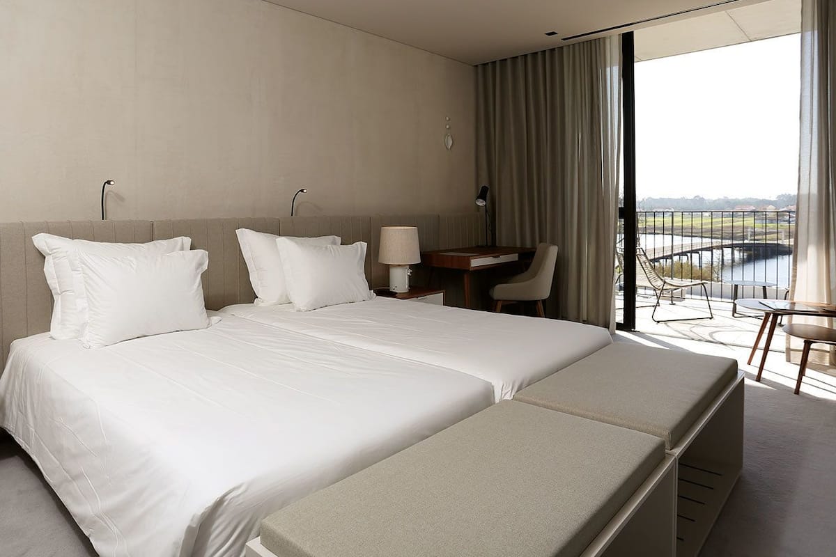 A hotel room with a large bed, a desk, and a view of a body of water.