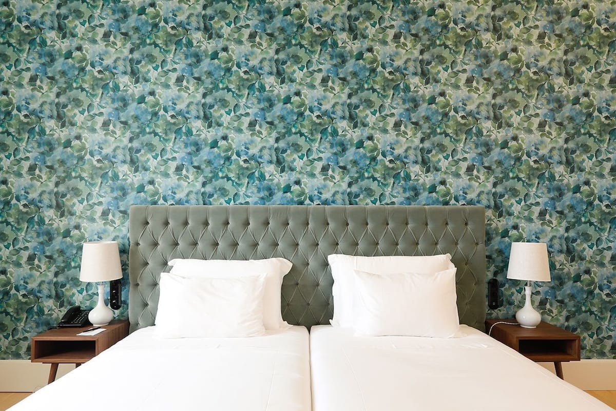 A double bed with a tufted headboard, white linens, and two bedside tables with lamps.