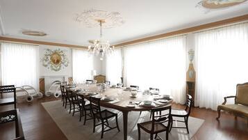 A formal dining room with a long table set for a meal, surrounded by chairs, and a chandelier.