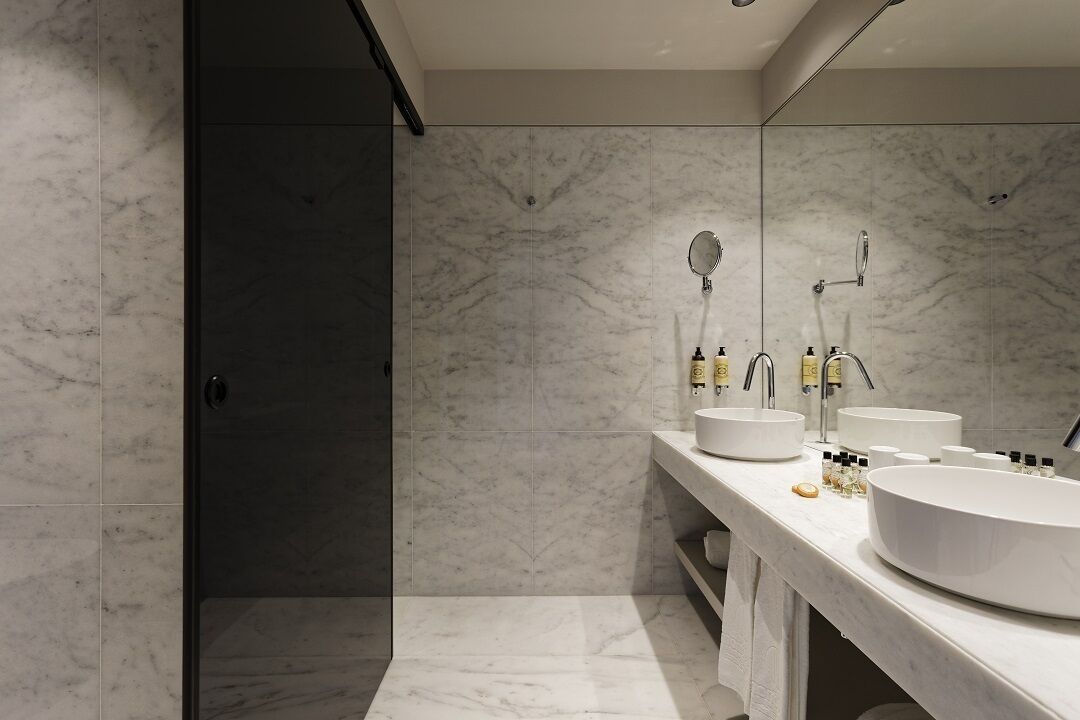 A modern bathroom with two sinks, a large mirror, and a shower area.