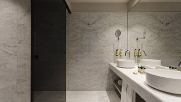 A modern bathroom with two sinks, a large mirror, and a shower area.
