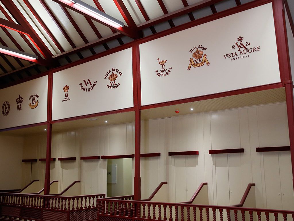 Een trap met rode leuningen en witte muren, voorzien van logo's van verschillende voetbalclubs.