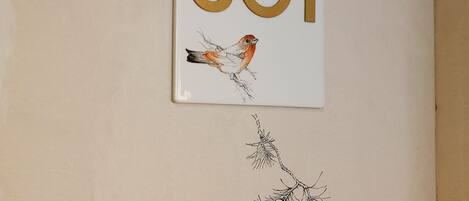 Un mur orné d’un panneau indiquant le numéro « 301 » et de deux illustrations d’oiseaux.