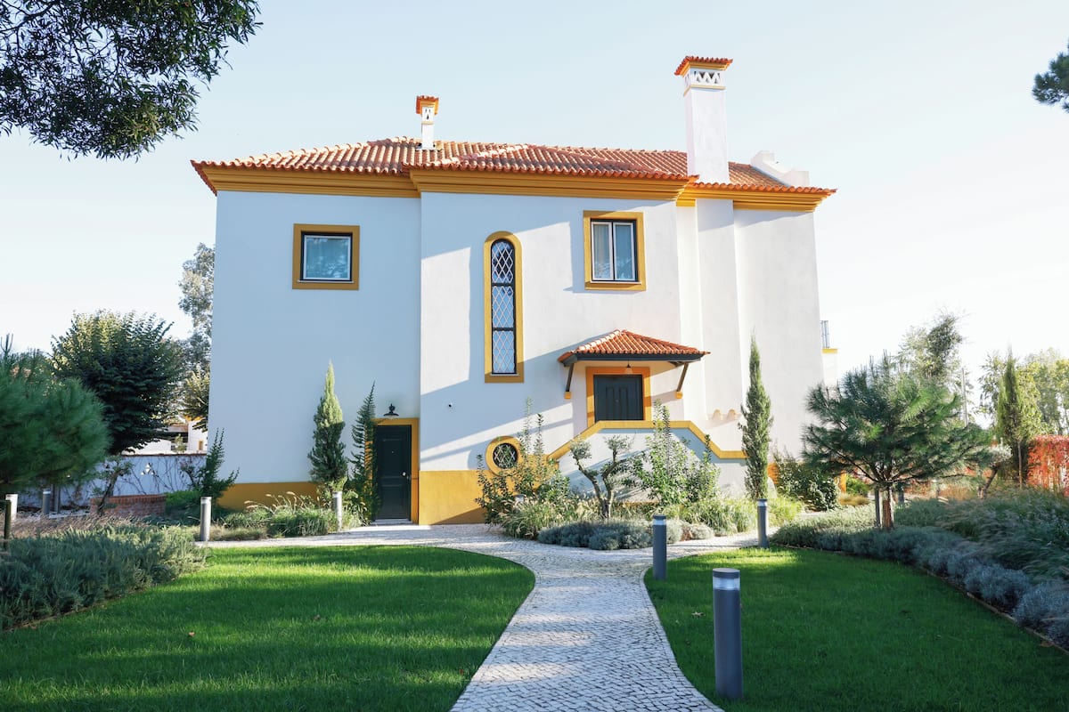 A two-story house with a tiled roof, a front entrance, and a paved driveway.