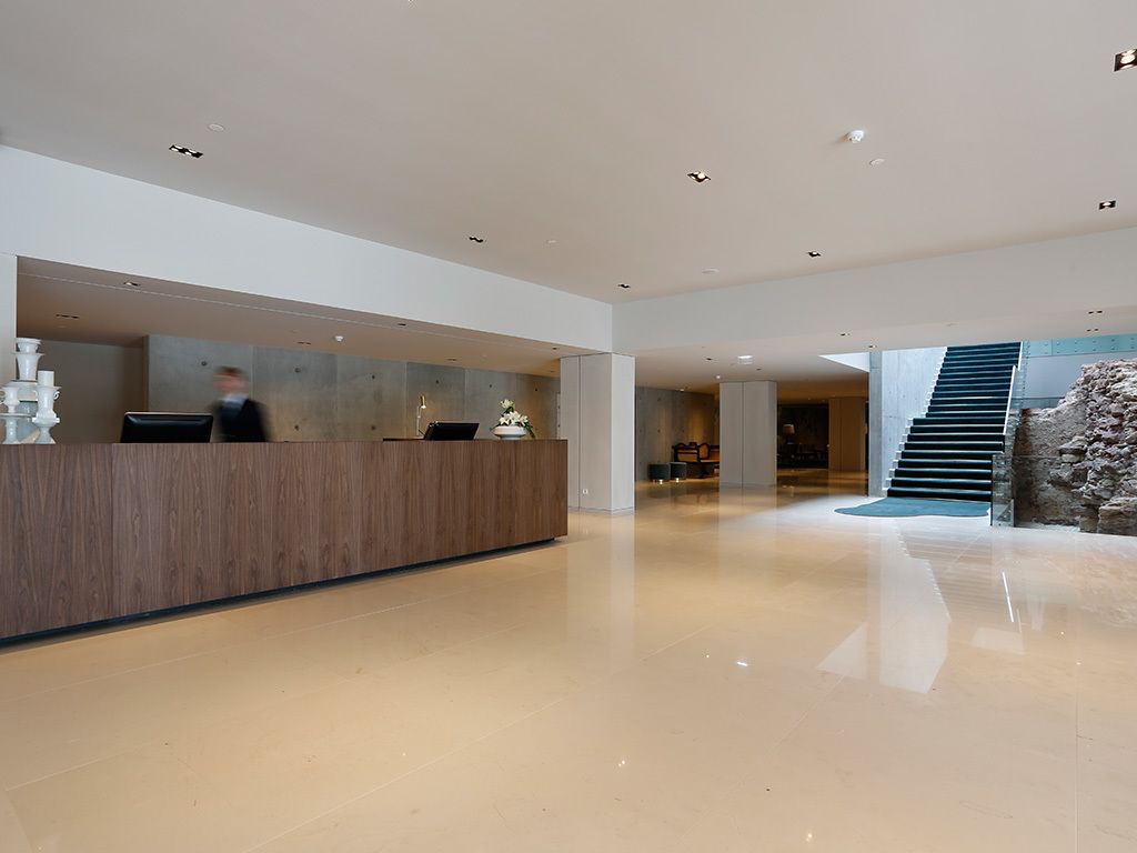 Un área de recepción moderna con un mostrador de madera, una escalera y una pared de piedra.