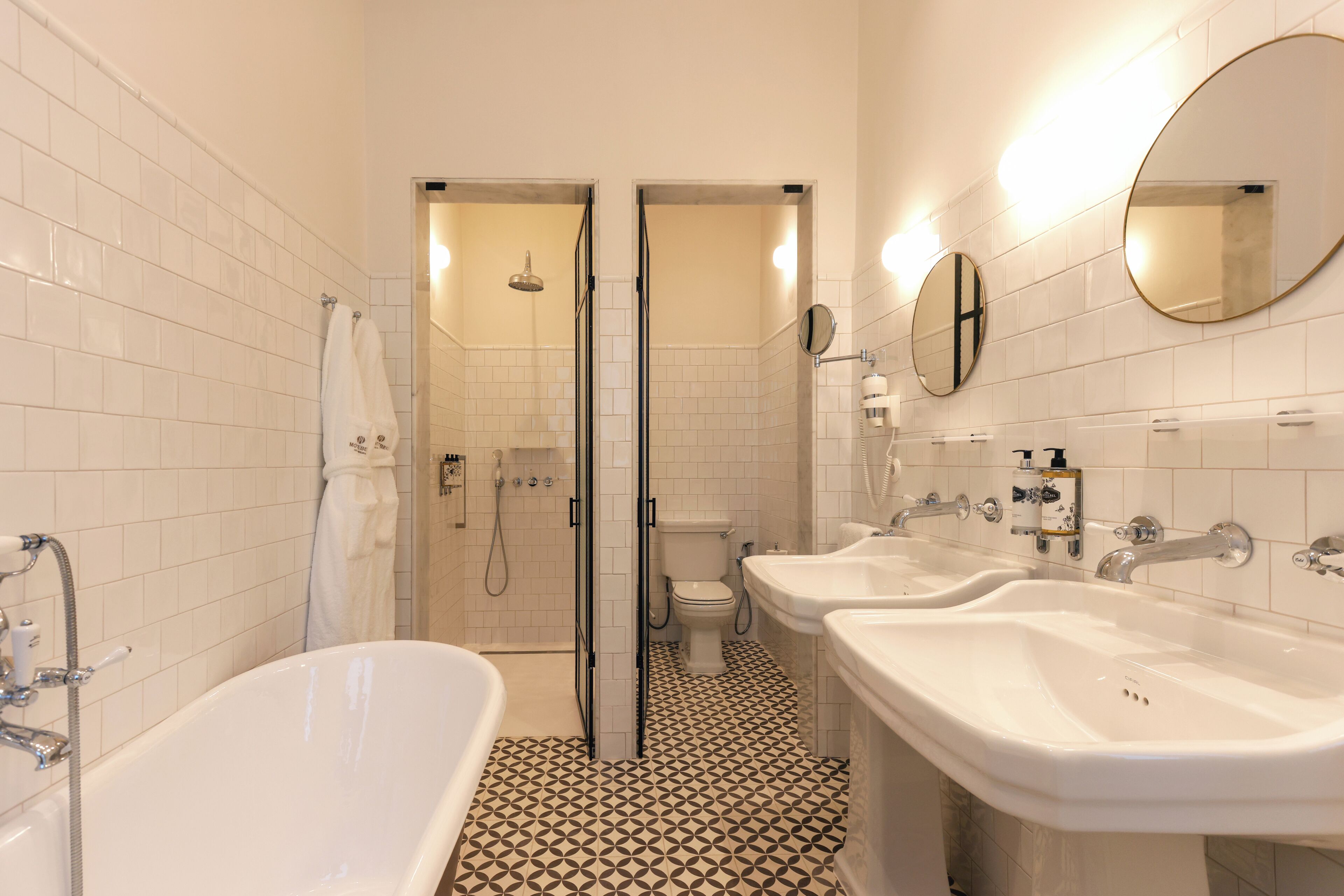 A bathroom with a bathtub, two sinks, a toilet, and a shower.