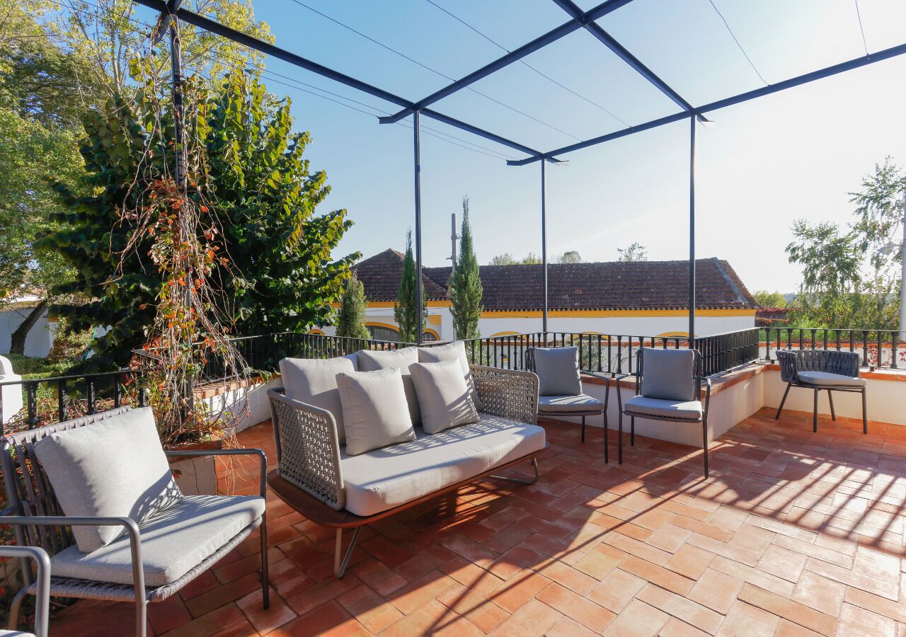Un área de patio al aire libre con un sofá, sillas y una estructura de pérgola.