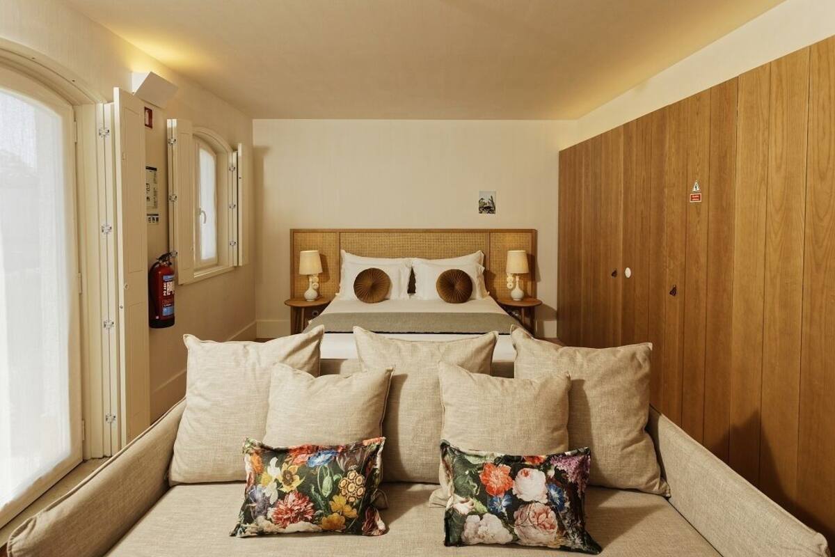A bedroom with a bed, two bedside tables, a wooden wardrobe, and a window.