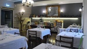 A restaurant with multiple tables set for dining, a bar area, and a large mirror on the wall. - Hotel Boavista - Vintage House (Idanha-a-Nova)