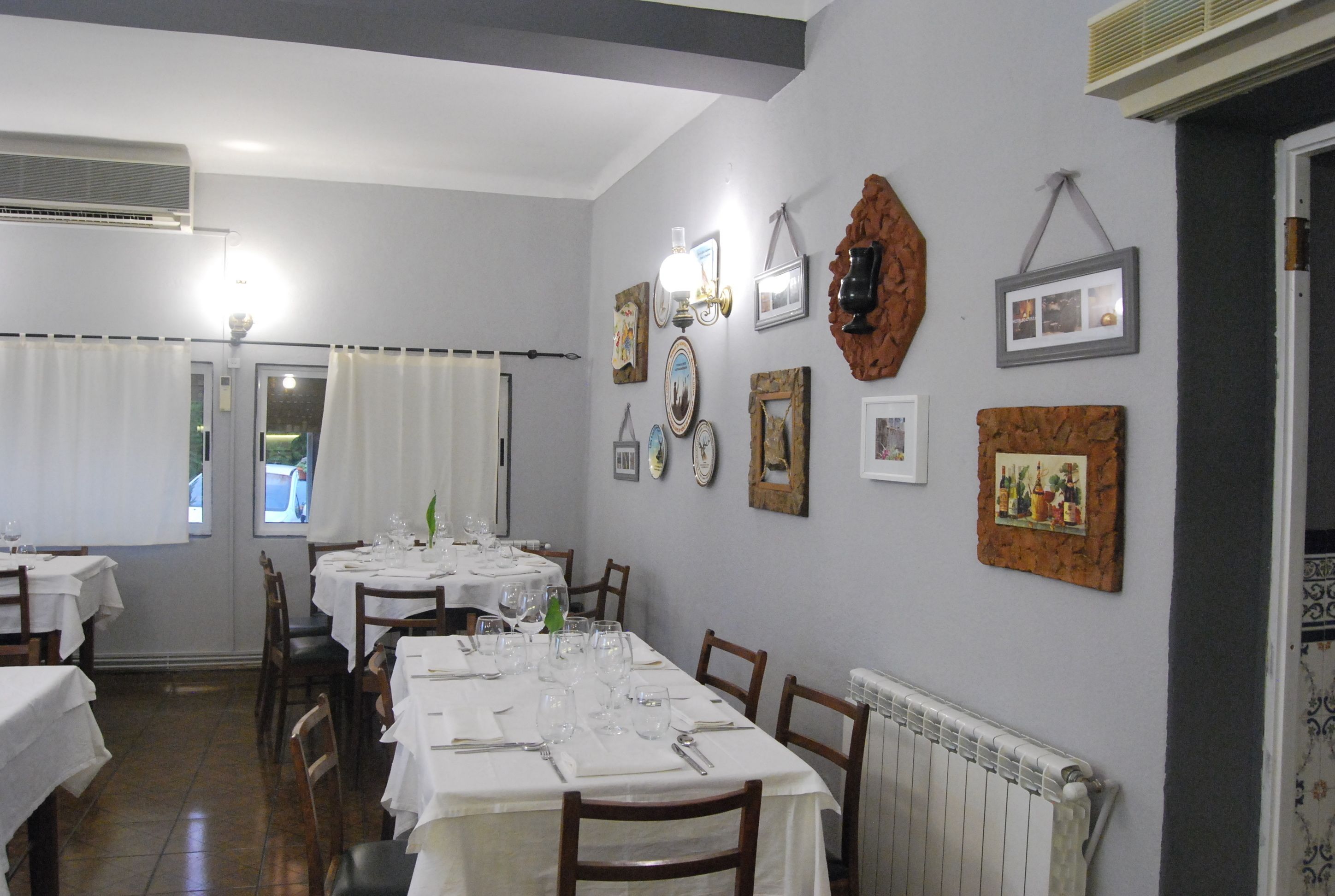 A dining area with tables set for meals, chairs, a radiator, and wall-mounted decorations.