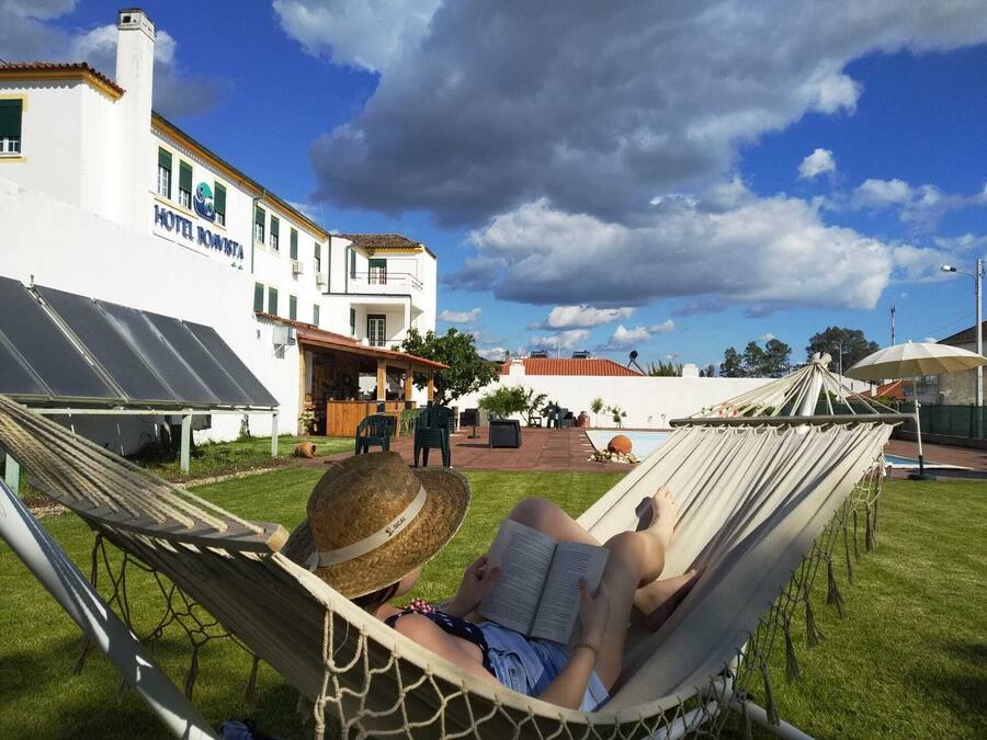 A hammock with a person reading, a pool, and a building labeled "HOTEL BOATSTA".