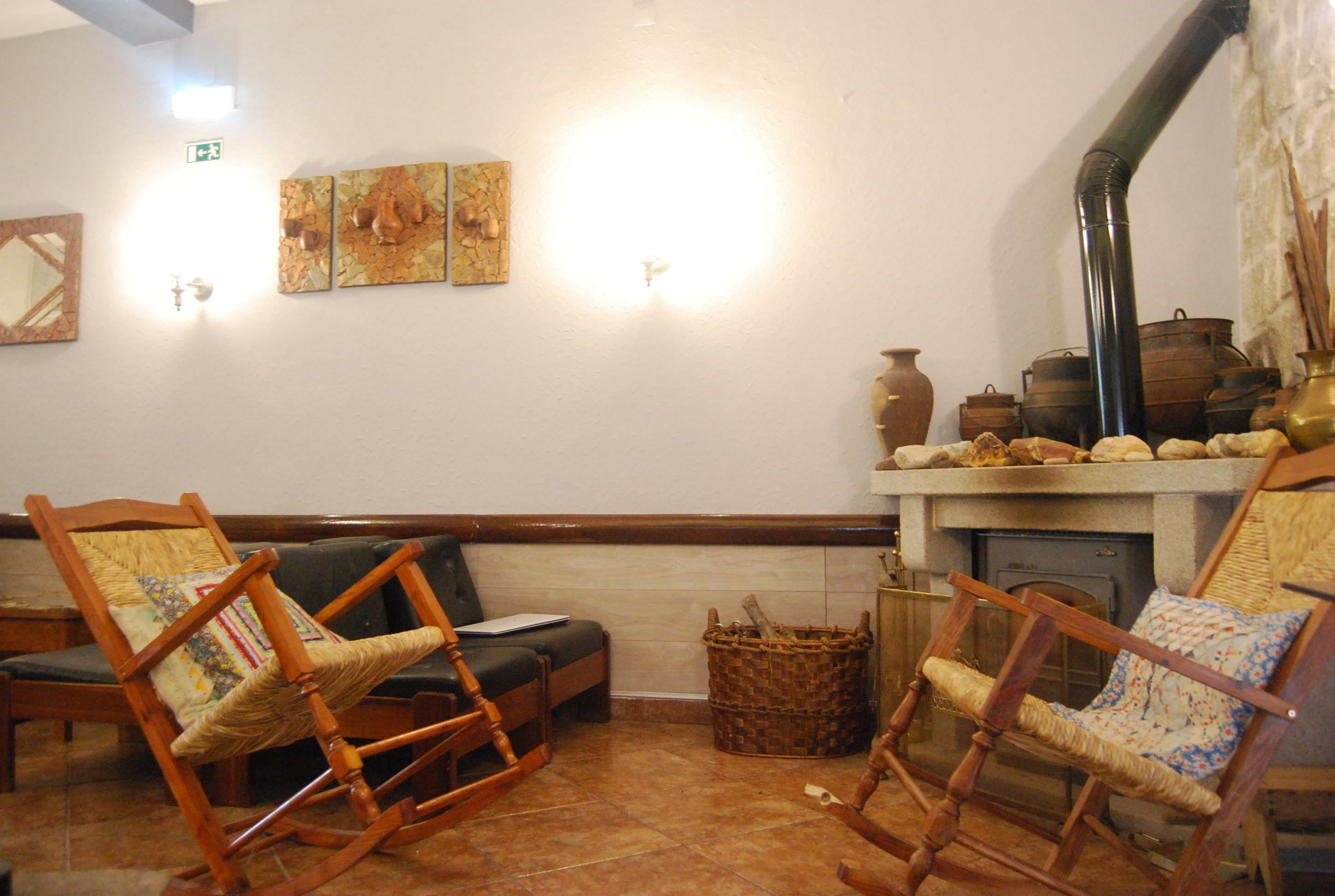Une pièce chaleureuse avec une cheminée, des fauteuils à bascule en bois, un canapé et des œuvres d’art accrochées aux murs.