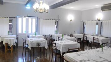 Un comedor con varias mesas dispuestas para el servicio, cada una con manteles blancos y cubertería.