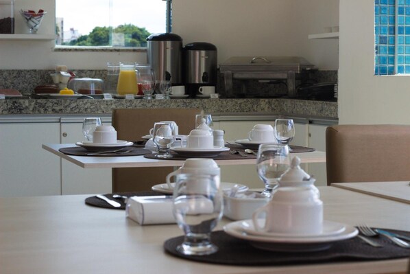 Une table mise pour le petit-déjeuner, avec de l’assiette, des tasses et une cafetière, préparée pour deux personnes.