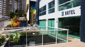 Un hotel moderno con fachada de vidrio, un mural colorido y vistas claras del entorno urbano.