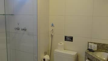 A bathroom with a glass shower enclosure, a toilet, and a sink with a towel rack.
