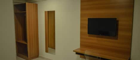 Ein modernes Zimmer mit einem eingebauten Holzschrank, einem an der Wand montierten Fernseher und einem klaren Stuhl.