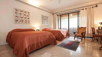 A hotel room with two beds, a desk, a chair, and artwork on the walls.