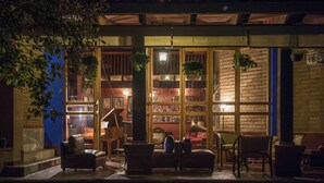 An outdoor seating area with a piano, chairs, and hanging plants. - Orchidelirium Casa Hotel & Salud Estetica (Cuernavaca)
