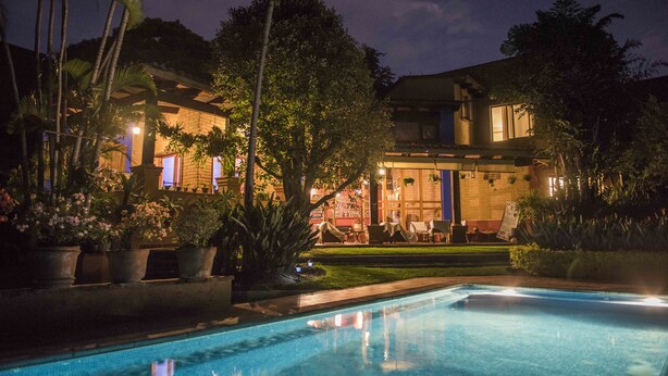 A nighttime view of a hotel with a swimming pool, lush greenery, and a well-lit outdoor seating area. - Orchidelirium Casa Hotel & Salud Estetica (Cuernavaca)