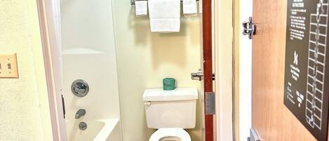 A bathroom with a toilet, a shower, and a towel rack.