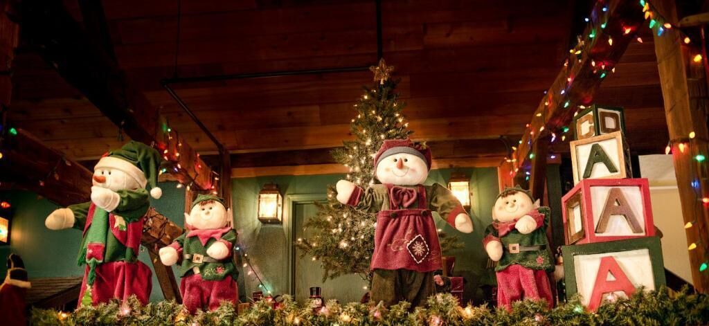 Una habitación con un árbol de Navidad, decoración festiva y una figura grande de muñeco de nieve.