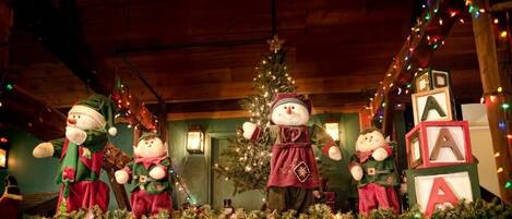 Una habitación con un árbol de Navidad, decoración festiva y una figura grande de muñeco de nieve.