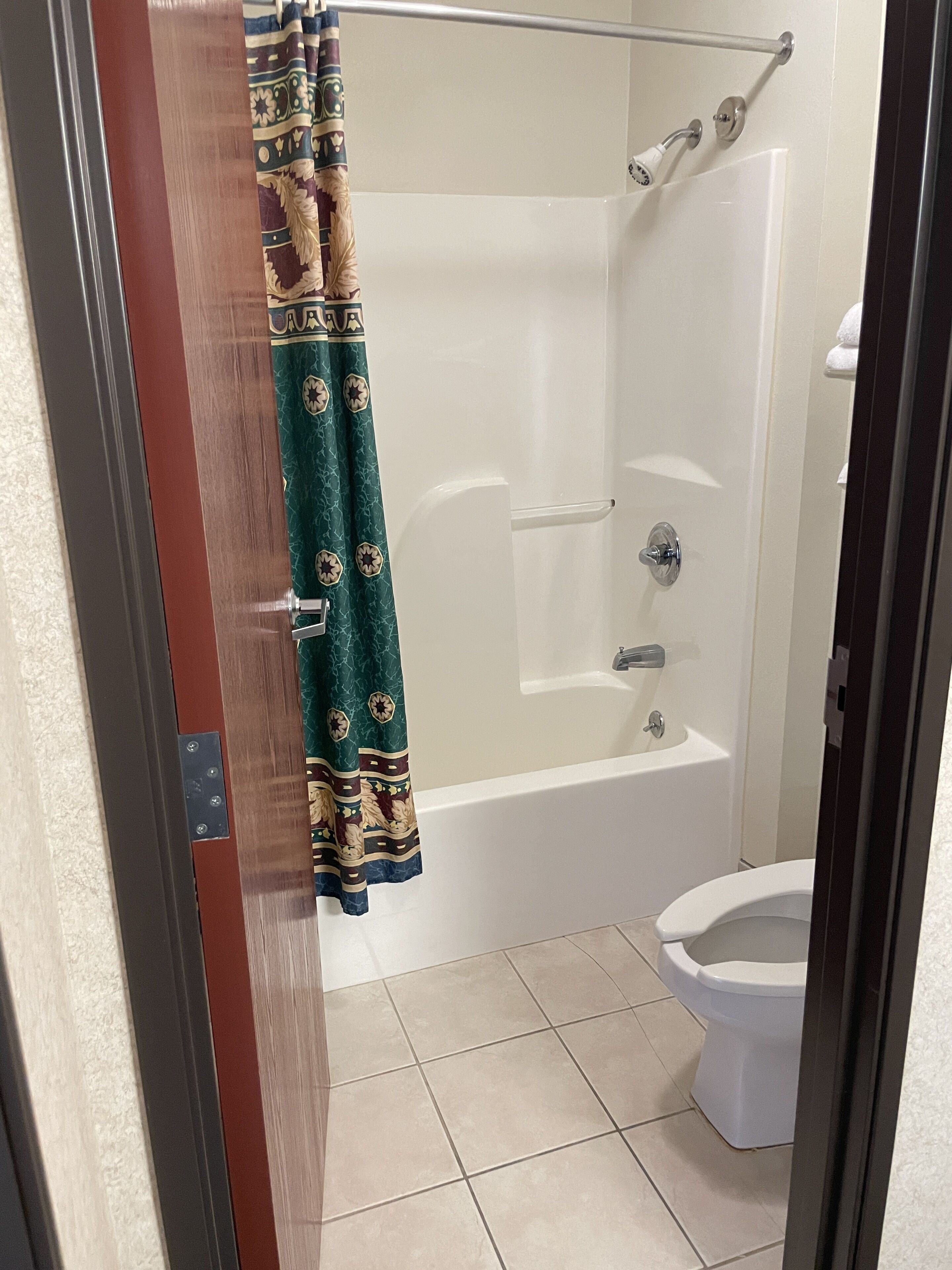 Un baño con ducha, inodoro y cortina de estampado geométrico.