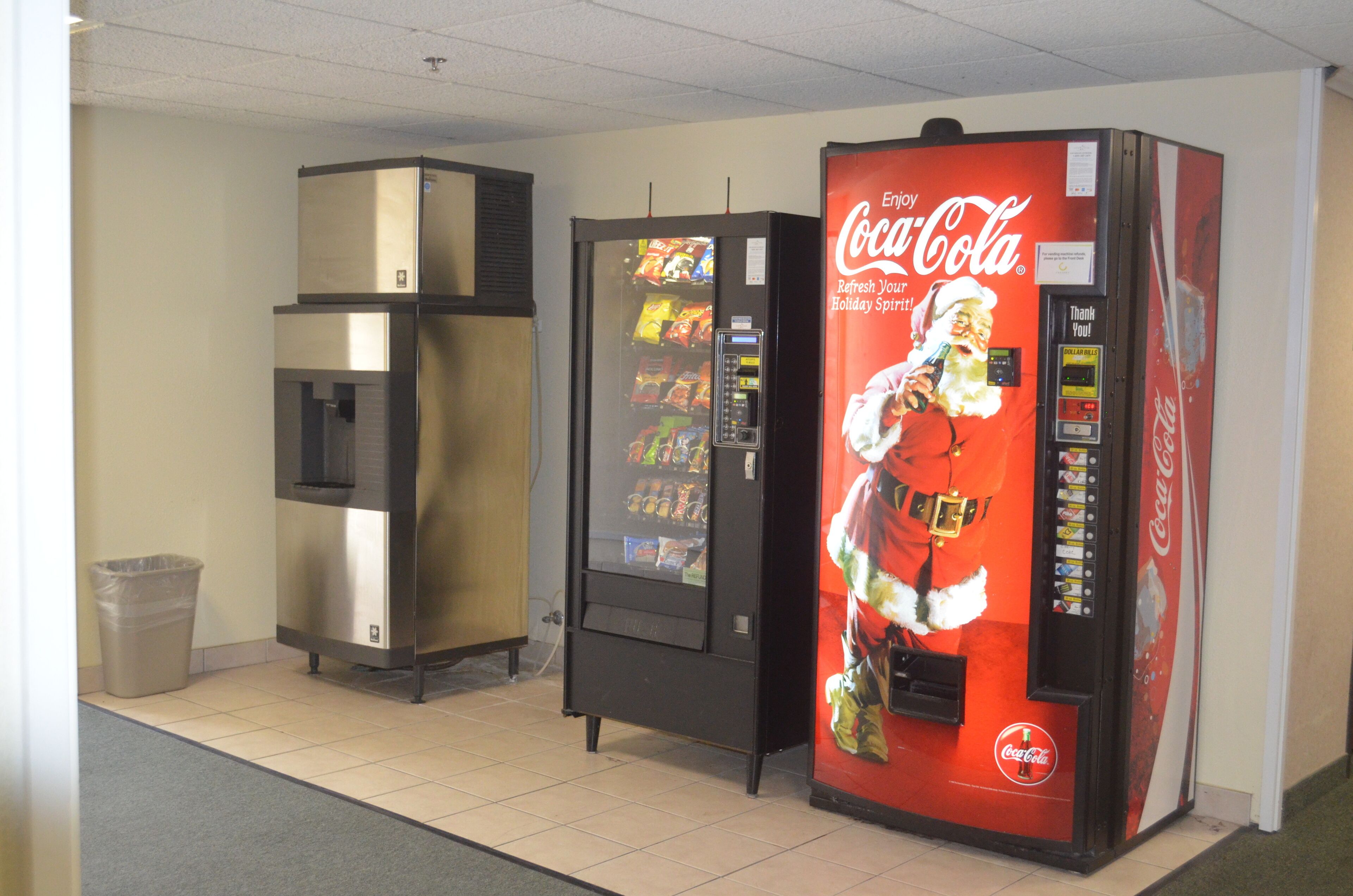 Un espace comprenant un distributeur automatique de boissons, notamment de Coca-Cola, et un réfrigérateur.