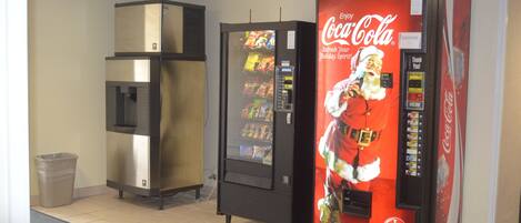 Un espace comprenant un distributeur automatique de boissons, notamment de Coca-Cola, et un réfrigérateur.