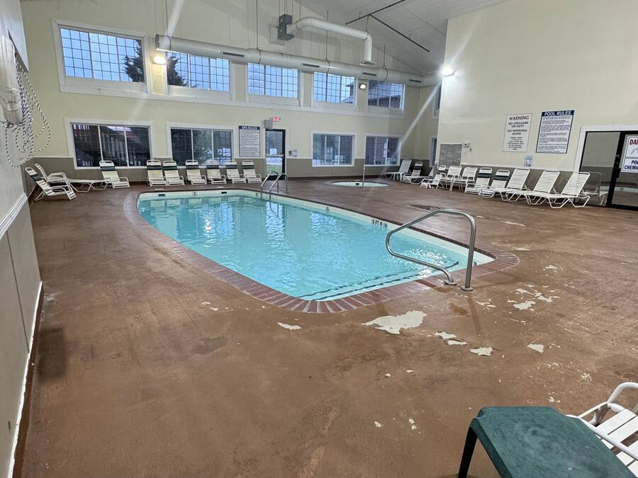 Una piscina interior con varias pistas de natación, rodeada de sillones de descanso y suelo de hormigón.