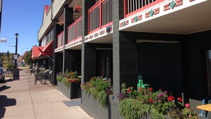 A building with a balcony, outdoor seating, and hanging flower baskets.