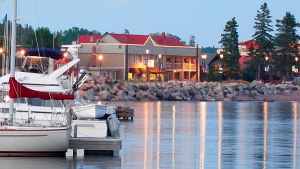 A waterfront property with a dock, boats, and a building with a red roof.