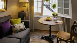 A room with a sofa, a table with a plate of lemons, a lamp, and a window with a view of a staircase. - Casa Goliana Boutique Hotel (Mexico City)