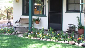 A building with a porch, a bench, a potted plant, and a flower bed. - Kern Riverfront Lodge (Kernville)