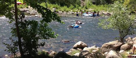 Un río con gente en balsas inflables, rodeado de rocas y árboles.