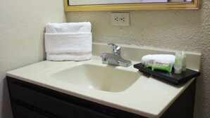 Un lavabo amb taulell blanc, un aire de metall platejat i un suport de tovalloles amb una tovallola blanca. Hi ha productes de tocador vora el lavabo.