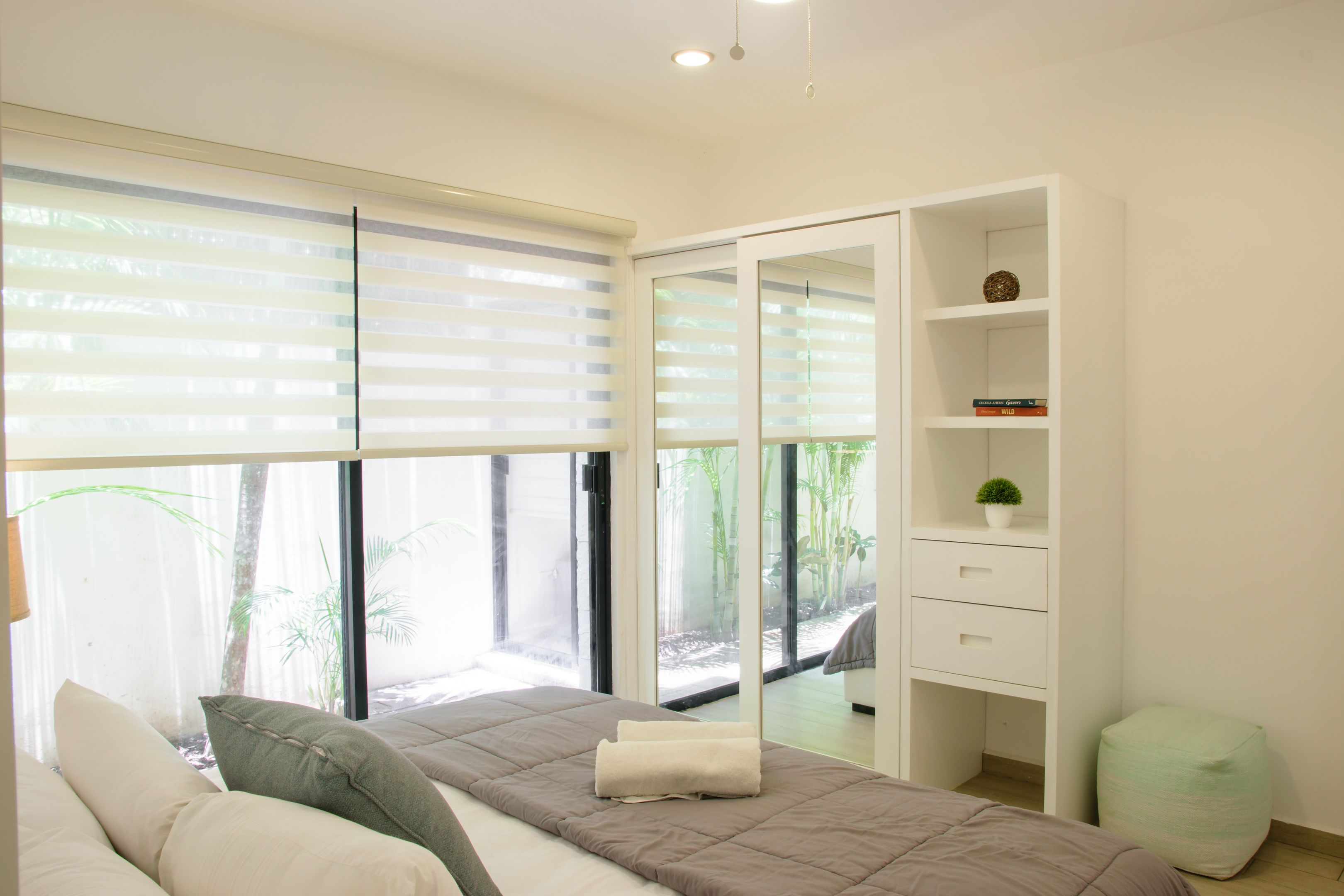 Un dormitorio moderno con cama, mesita de noche, armario y ventana con persianas.