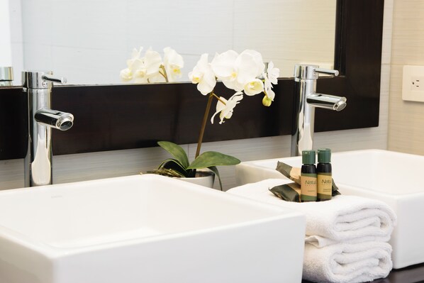 Un baño moderno con dos lavamanos, un espejo y una orquídea en maceta.