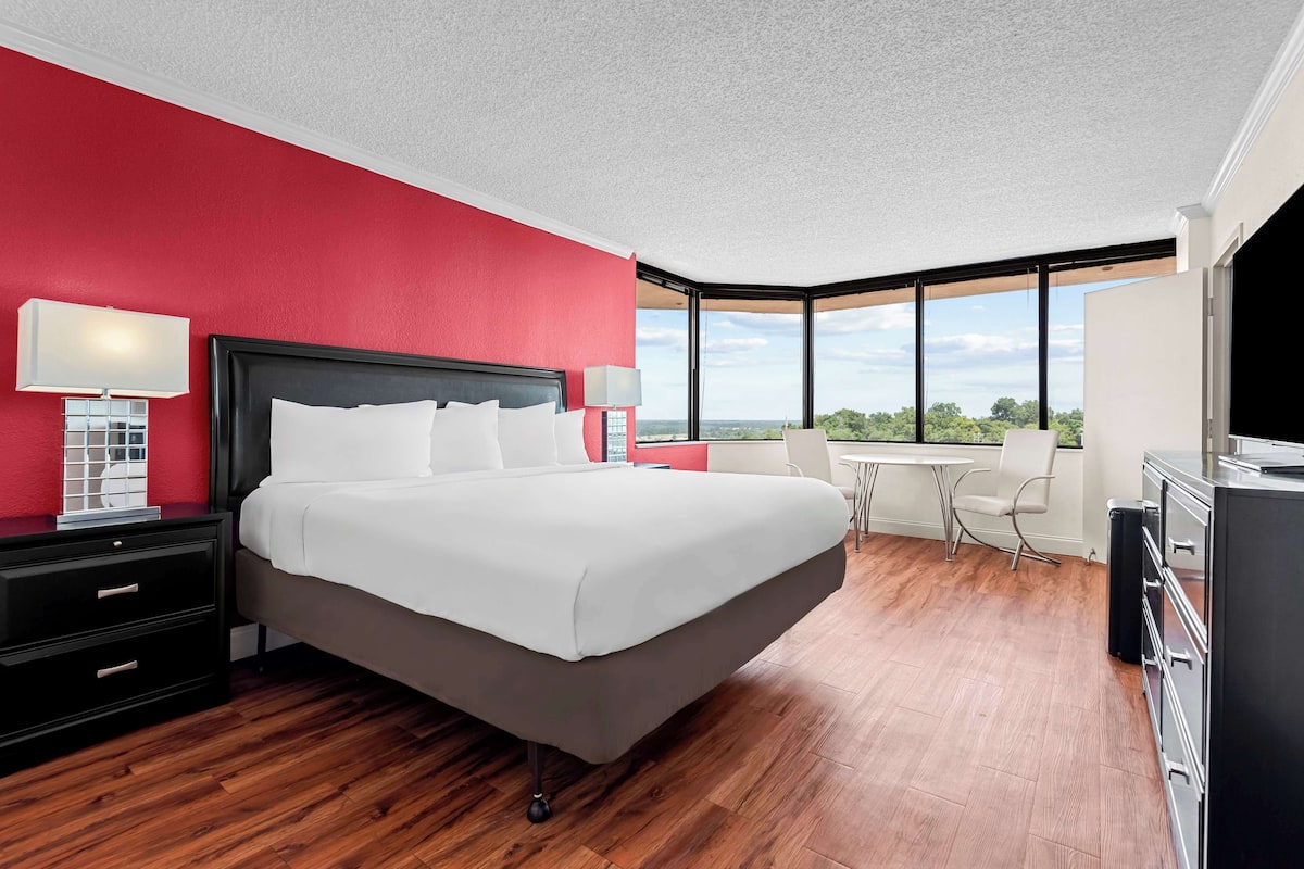 Una habitación de hotel moderna con una cama grande, un escritorio y vistas al exterior.