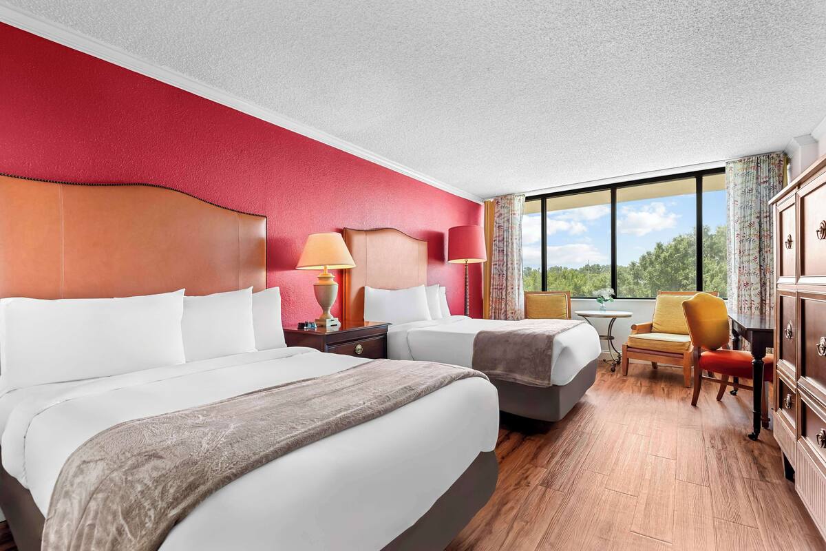 Una habitación de hotel con dos camas, un escritorio, una silla y un armario.