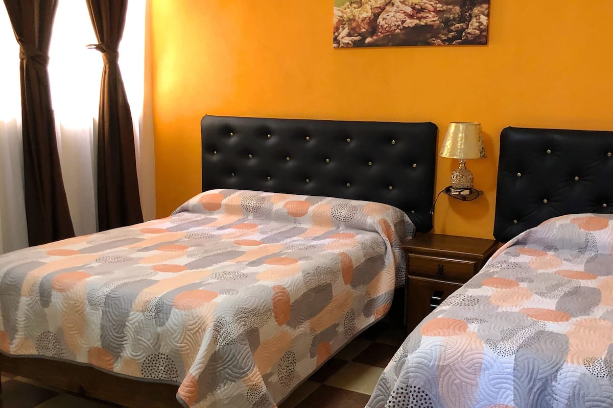 Une chambre d’hôtel avec deux lits, un tableau au mur et un sol à carreaux.
