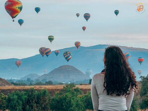 A person standing in a field with multiple hot air balloons in the background. - Hotel Jatziri Teotihuacan (Teotihuacan)