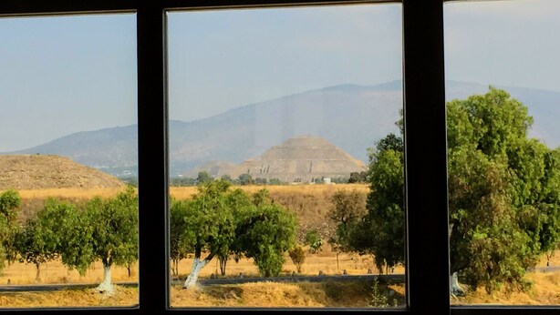 A view through a window with a landscape of hills, trees, and a clear sky. - Hotel Jatziri Teotihuacan (Teotihuacan)