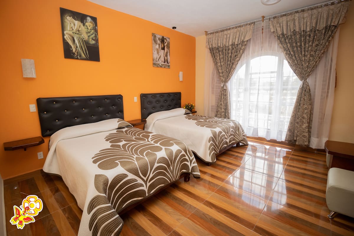 Une chambre d’hôtel avec deux lits, un plancher en bois et des œuvres d’art accrochées aux murs.