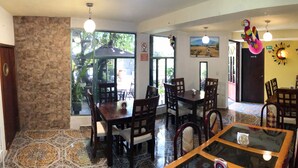 A dining area with wooden tables and chairs, a glass coffee table, and a stone wall. - Hotel Jatziri Teotihuacan (Teotihuacan)