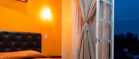 Une chambre à coucher avec un lit, un tableau accroché au mur et une vue sur l’extérieur.