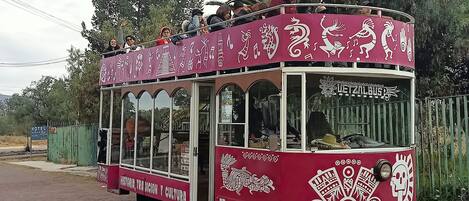 A red bus with cultural designs and text in Spanish, parked on a road.