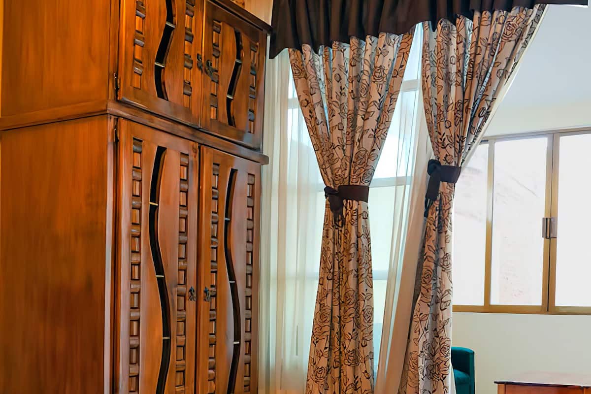 Une chambre à coucher avec un grand lit, une armoire en bois et des rideaux à motifs floraux.